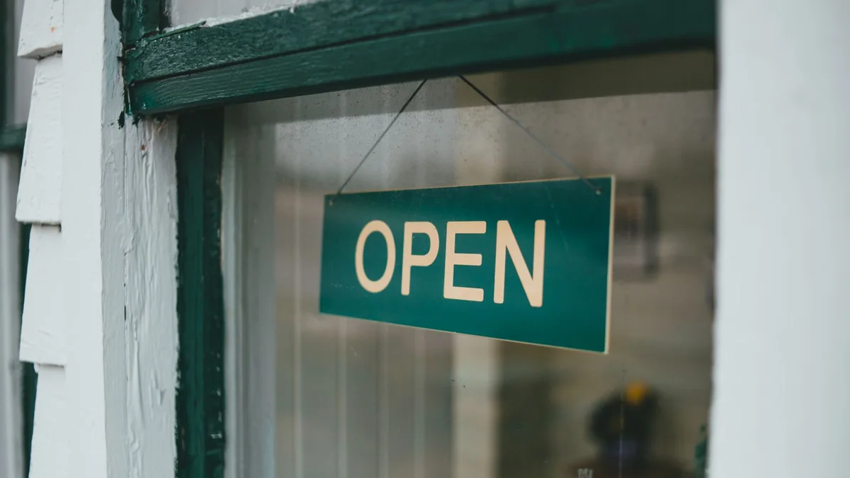 Panneau Open accroché derrière la vitre d'une boutique déserte